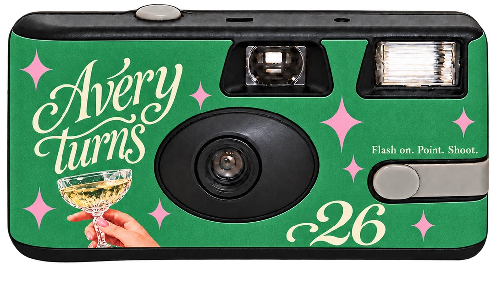 Front of a disposable camera: a green Avery turns 26 sticker with a champagne coupe and pink sparkles