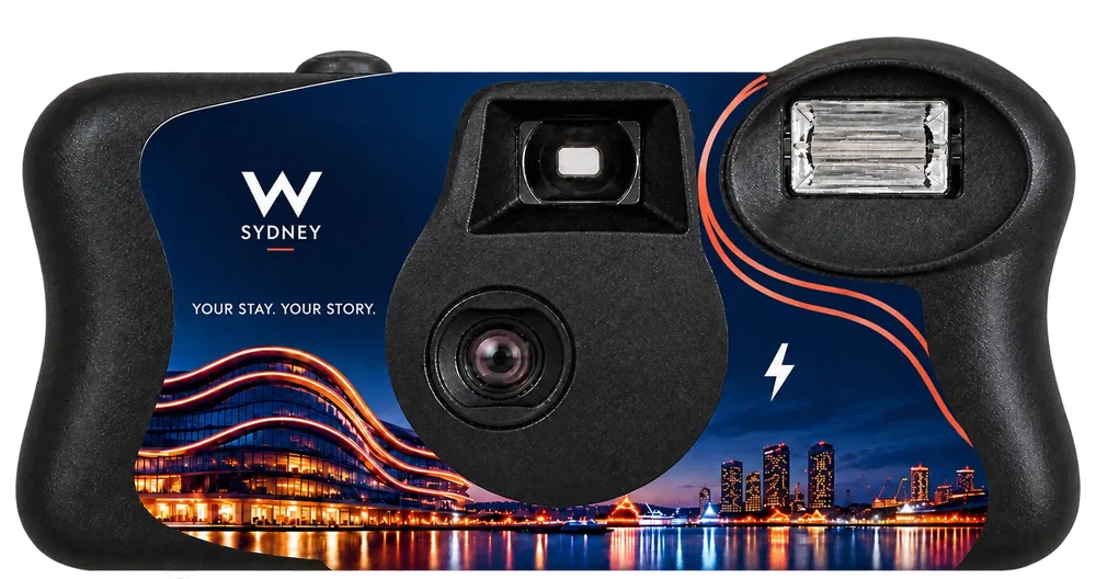 A Stay Pack camera: a W Sydney sticker reading Your stay. Your story., with the hotel lit up at night