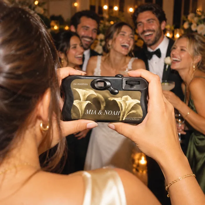 A guest photographing the couple and their friends mid-laugh at the reception